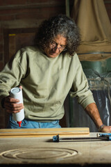 Man gluing wooden board at carpenter's shop