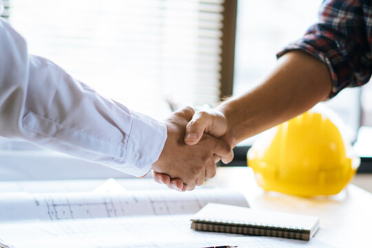 Client shaking hands with contractor after confirm blueprint to renovate house.