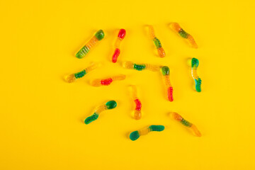 Fruit flavored worm shape, jelly candies. Isolated on yellow background.