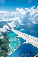 View from a plane window of a wing over an island with turquoise ocean, white clouds in the blue sky