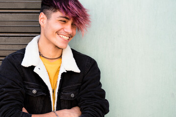One young guy teenager standing against a wall and garage door looking on camera with trendy hair...