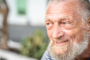 Side portrait of old happy man smiling and looking outside. Aged mature male introspection...