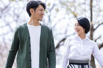 桜並木の下を歩く男女