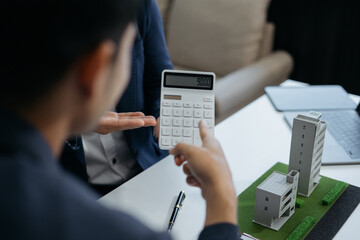 Real estate broker agent presenting and consult to customer to decision making sign insurance form agreement, home model, concerning mortgage loan offer in office.