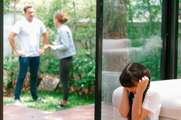 Stressed and unhappy young girl huddle in corner, cover her ears blocking sound of her parent...