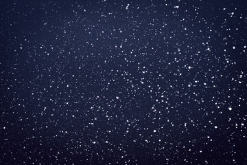 Natural snow particles in the air. Dark blue fading to black background
