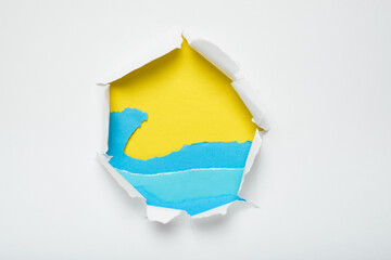 Hole in white paper showing a beach landscape created with torn paper. Colorful summer background.