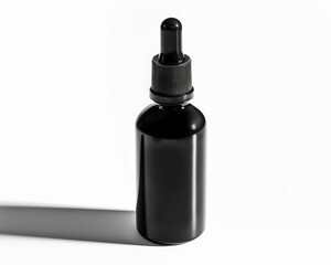 Modern black dropper bottle isolated on white, with high contrast shadows for dramatic advertising