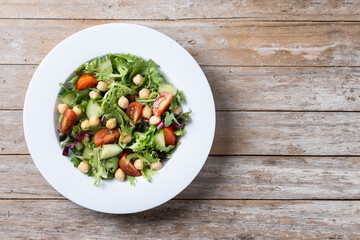 Healthy chickpea salad with tomato,lettuce and cucumber on wooden table. Top view. Copy space