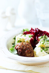 Hamburger steak with potatoes and fresh herbs on bright background. Close up.	