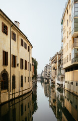 Fototapeta na wymiar The city canal San Massimo in Padua. Beautiful urban view of residential buildings with balconies in the center of the old city Padova, Veneto. Rivers Brenta and Bacchiglione, Italy