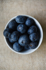 Blueberries in a white bowl on a burlap tablecloth. Juicy blueberries.