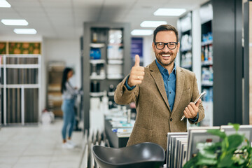 A male seller showing a thumb up to the camera and smiling, at the home design shop.