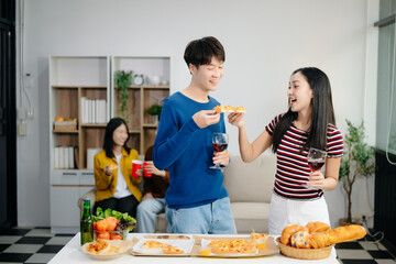 Young Asian friend having, enjoy evening party together at home. Attractive young man and woman having fun, eating food, celebrate at home