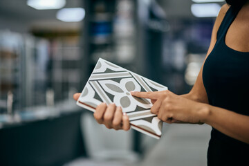 A female seller showing a ceramic tile with an interesting design.