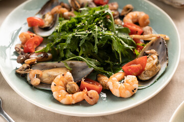 Seafood salad with shrimps and mussels with arugula on plate, close-up