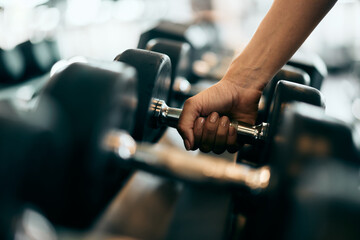 Close-up of a female hand picking up a heavy dumbbell.