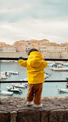 Petite fille de dos avec un ciré Jaune avec vue sur le vieux port de Dubrovnik