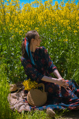 Outdoor picnic, girl revels in nature's beauty, beside her lies handmade round straw bag, crafted...