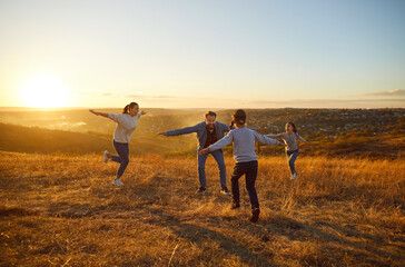 Blindfolded child boy catching his family playing hide and seek together outdoors. Happy children having fun with mom and dad walking in the field. Young parents with kids in nature at sunset.