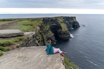 Woman enjoying the spectacular Cliffs of Moher, located in the southwestern corner of the Burren...