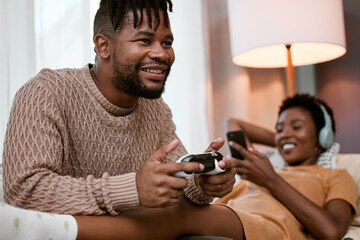Black couple, sofa and happy with entertainment for bonding, playing and streaming at home. Man, woman and together with relaxed on couch and phone for music, video games and fun in lounge in Nigeria