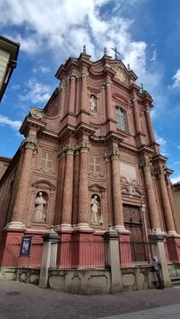 Chieri, metropolitan city of Turin, Piedmont, Italy. April 21, 2024. Vertical format footage featuring the red brick facade of the baroque style church of San Filippo Neri. Beautiful sunny.