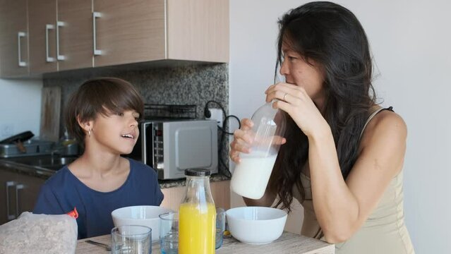 Pregnant woman and non-binary kid having breakfast at home