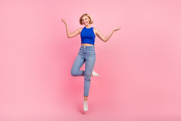 Full body portrait of nice girl jump arms show empty space wear blue top isolated on pink color...