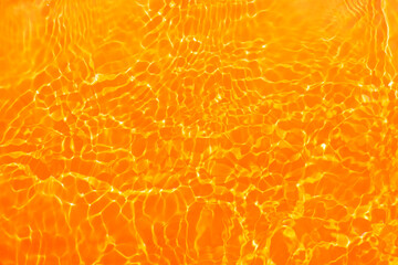  Yellow water with ripples on the surface. Defocus blurred transparent gold colored clear calm water surface texture with splashes and bubbles. Water waves with shining pattern texture background.