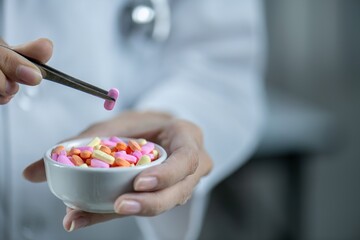 A doctor holding a bowl of pills with a pair of tweezers