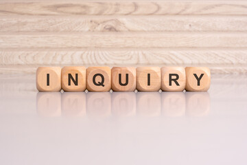 wooden blocks displaying the word 'Inquiry' arranged on a glossy gray surface