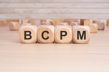 the acronym BCPM is elegantly displayed on a beige hardwood rectangle block