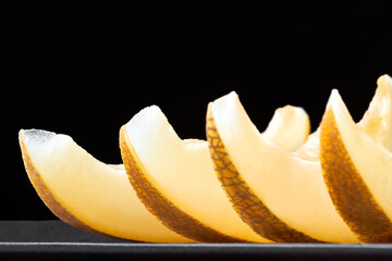 Melon slices on a wooden board on a dark background