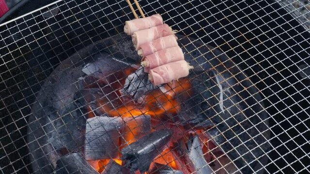 Top view video of hand grilling Korean meat barbeque skewers on a grill