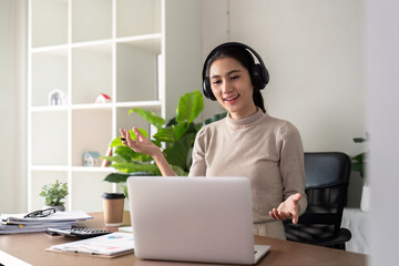Young businesswoman wearing headphones and discussing project detail with clients on video call. woman with headphones conducting online meeting with colleagues