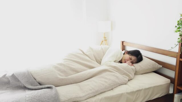 布団の中で寒気を感じる女性
