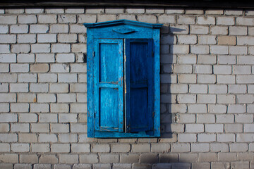 Street photo. Blue wooden old window with closed shutters on brick wall. Closure from world and...