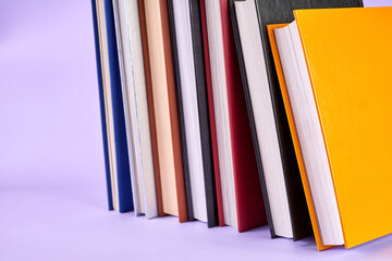 Stack of colorful books on purple background