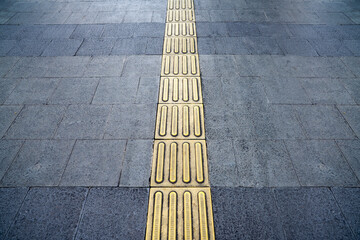 Footpath with yellow tactile paving for blind people walking safely on the sidewalk