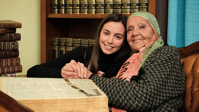 Foto scattata ad una nonna con sua nipote mentre leggono una raccolta di libri antichi.