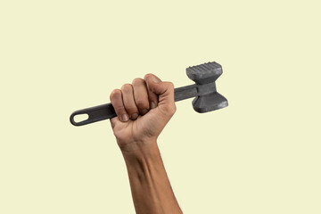 Black male hand holding a kitchen hammer isolated on green background
