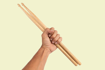 Black male hand holding wooden Drum sticks isolated on green background