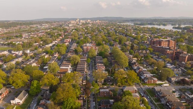 American city neighborhood during golden hour sunset. Aerial rising hyperlapse with people and traffic in suburb with row houses.