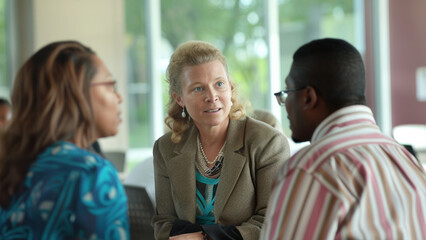 Engaged in conversation, three professionals discuss earnestly in a well-lit office setting.