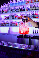 Bartender prepares alcoholic cocktail on bar counter