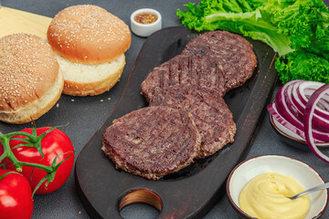 Grilled burger patties. Hot beef cutlets, buns, vegetables and sauce. Homemade American classic