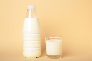 A glass and bottle of milk on beige background. Top view
