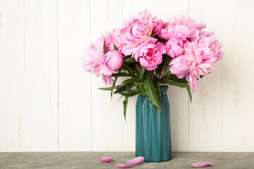 Vase with beautiful peonies on light background