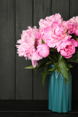 Vase with beautiful peonies on black wooden background
